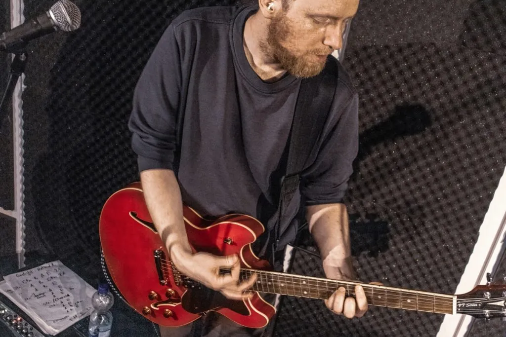 Daniel mit roter Halbresonanzgitarre im Proberaum