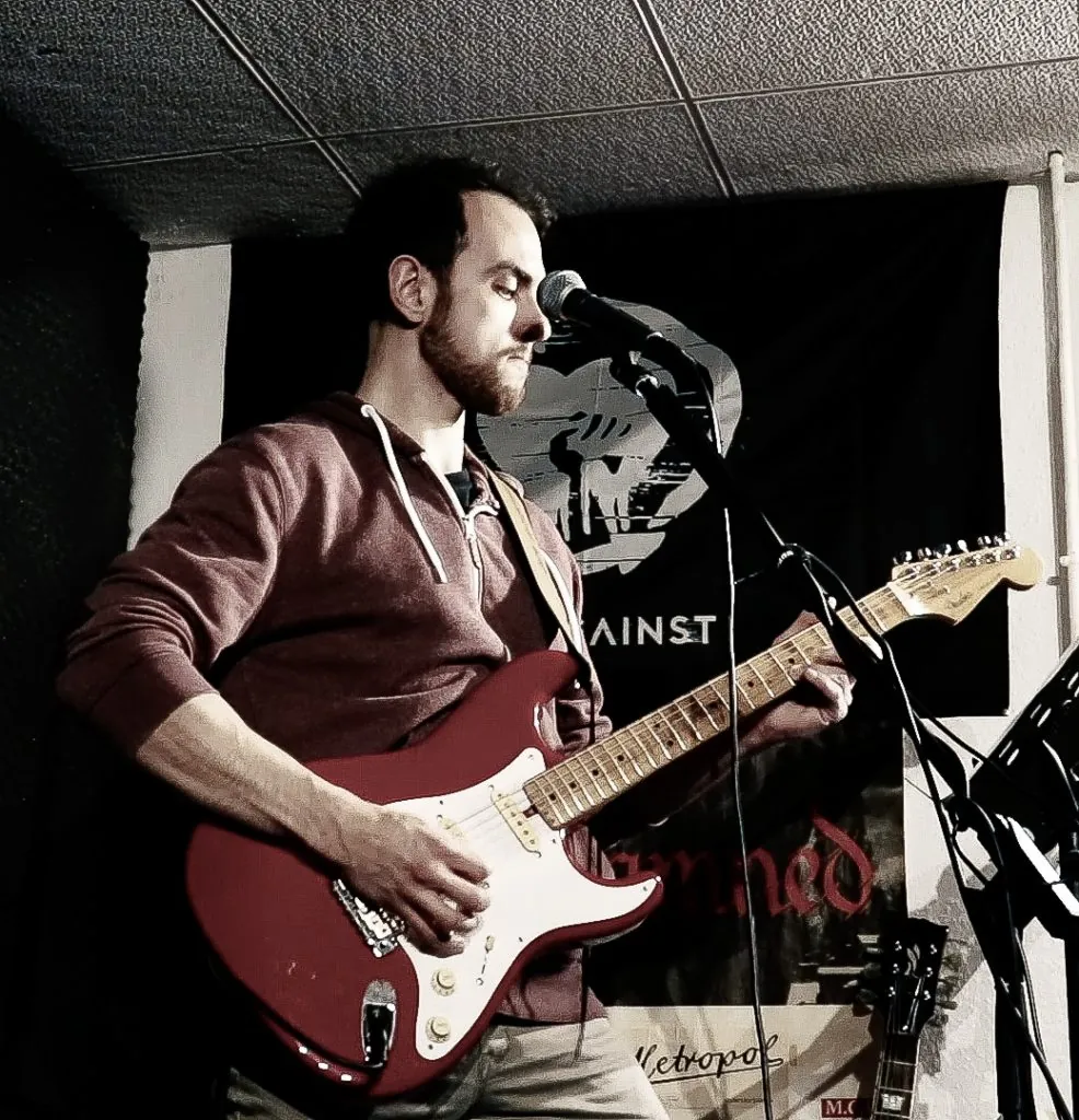 Eric singt und spielt eine rote Stratocaster