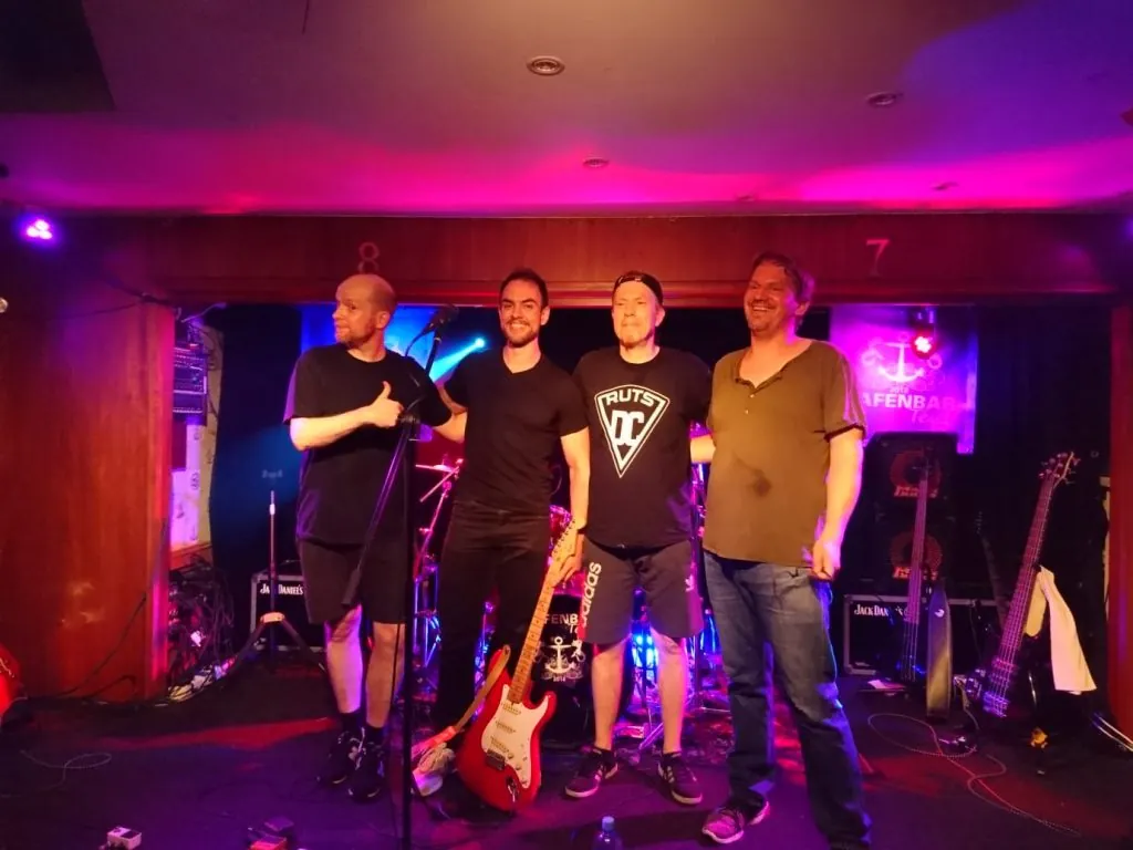 Daniel, Eric, Thomas und Michael nebeneinander auf der Bühne der Hafenbar