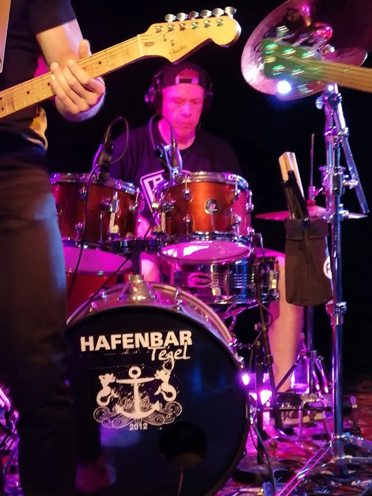 Thomas mit Kopfhörern am Schlagzeug, vorn die Bassdrum mit Hafenbar-Logo